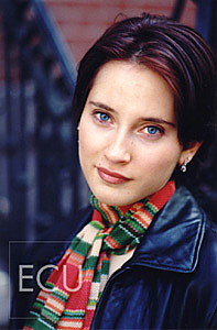 Color photograph of a brunette woman with blue eyes sitting on the stairs